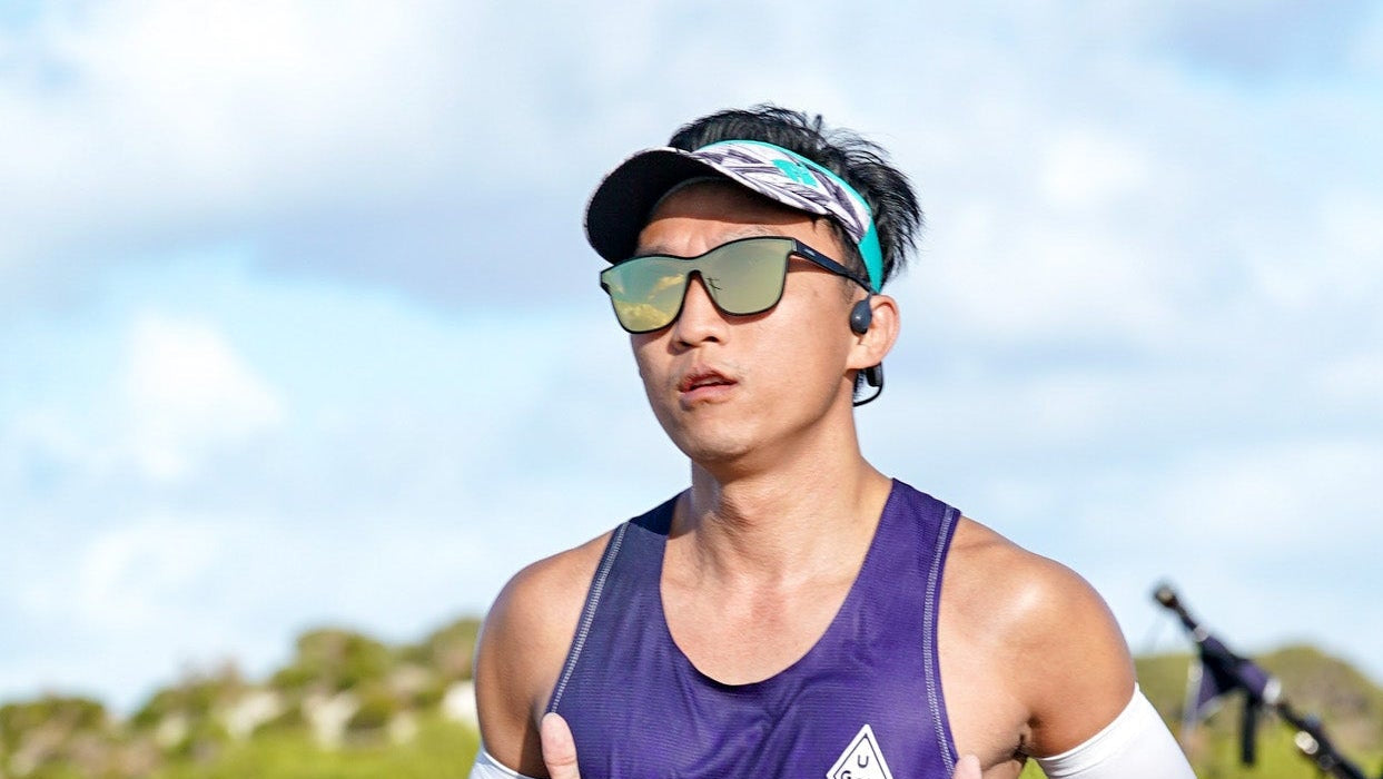 Person wearing sunglasses and a purple tank top outdoors with a clear sky.