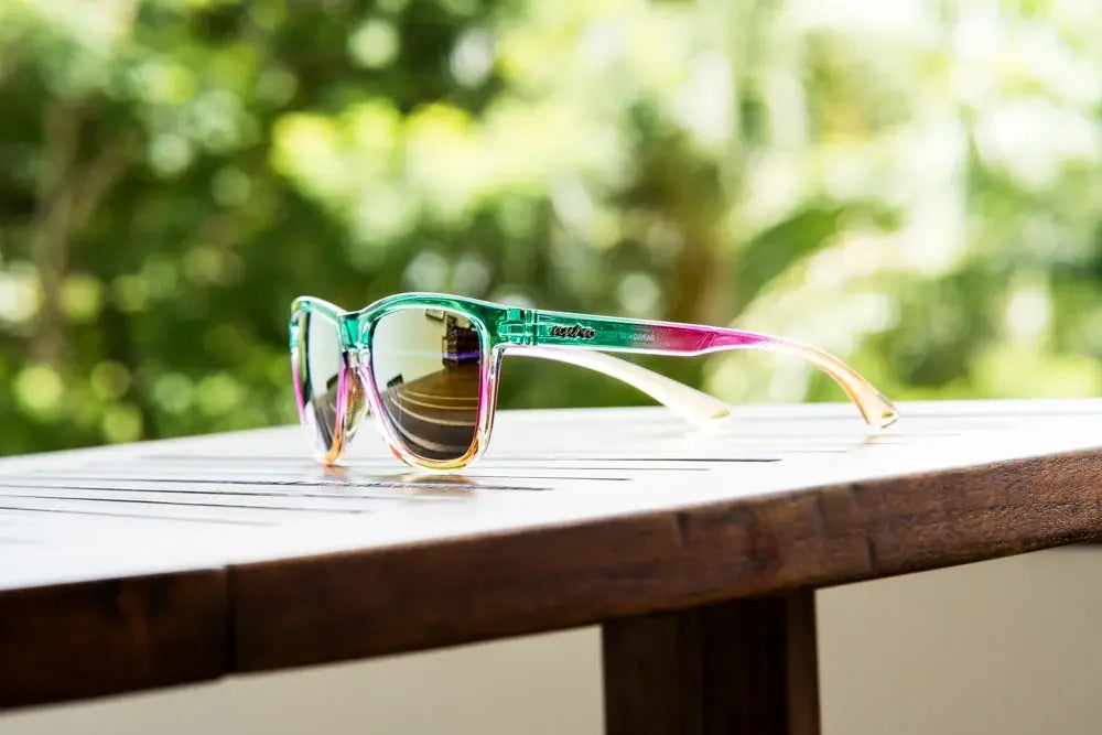 Colorful gradient sunglasses with polarized lenses on a wooden table outdoors