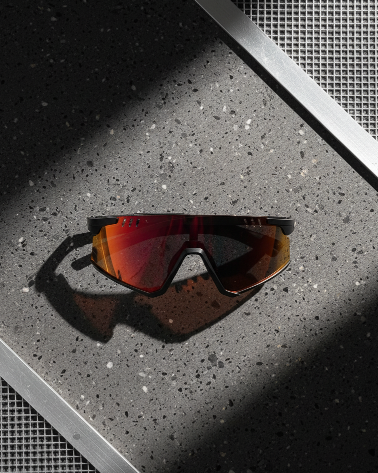 Sunglasses with red lenses on a textured surface with carbon fiber frames