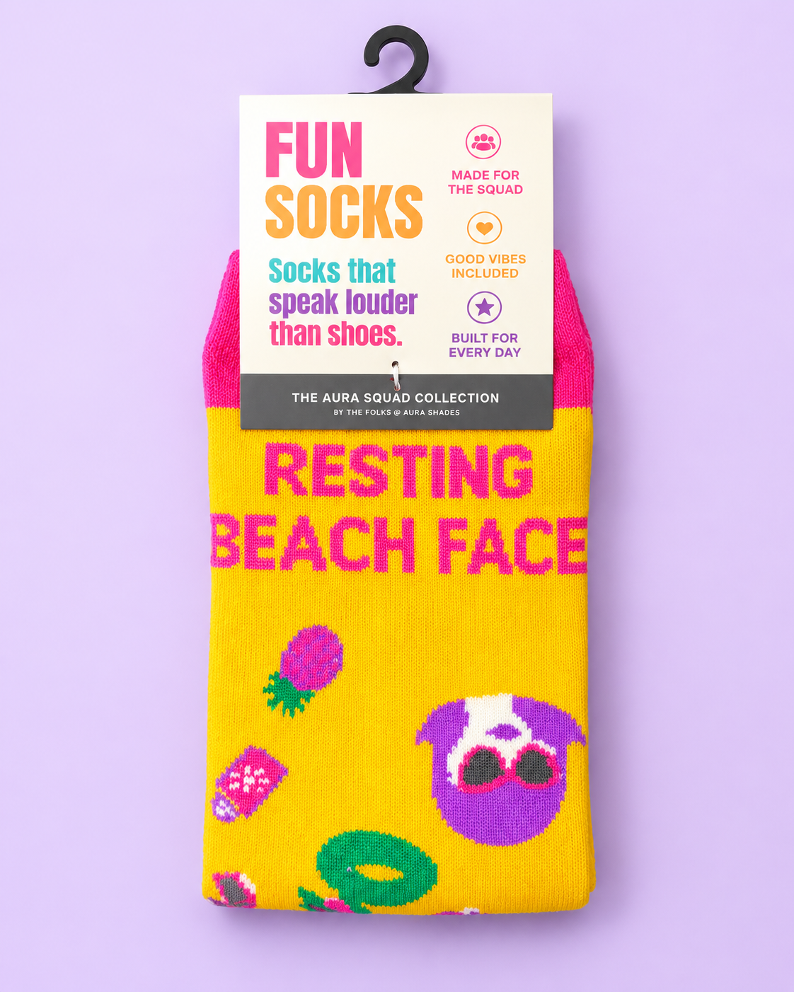Resting Beach Face crew socks by Aura Shades in yellow with a pink cuff, featuring a dog in heart sunglasses, pineapple and pool ring graphics, in The Aura Squad Collection packaging