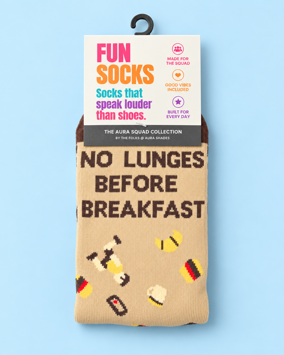 No Lunges Before Breakfast crew socks by Aura Shades in beige with brown lettering and dumbbell, croissant and coffee graphics, in The Aura Squad Collection packaging