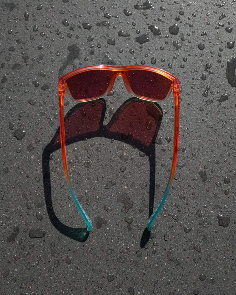 Sunglasses with red lenses and orange colorful frame on a textured black surface