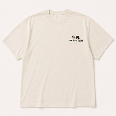 An off-white short-sleeve crewneck t-shirt featuring a small black graphic of two faces and the text 'THE AURA SQUAD' printed on the left chest, displayed against a clean off-white background.