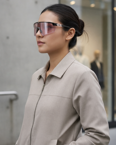 Woman wearing a beige coat and pink sunglasses in an urban setting
