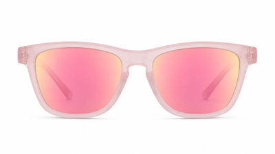 A pair of square-frame sunglasses with a translucent light pink frame and mirrored pink lenses that reflect a warm gold/orange hue, shown against a plain white background.